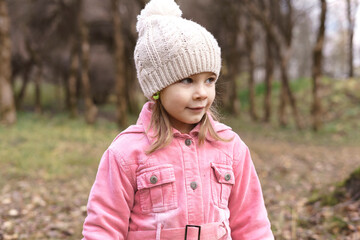 portrait of a little caucasian girl in a knitted hat in an autumn park