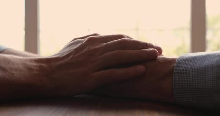 Adult son touches hands of elderly dad close up. Grown up child tell important words of love, give support empathy, share and overcome together life troubles, relieve worries to old relatives concept