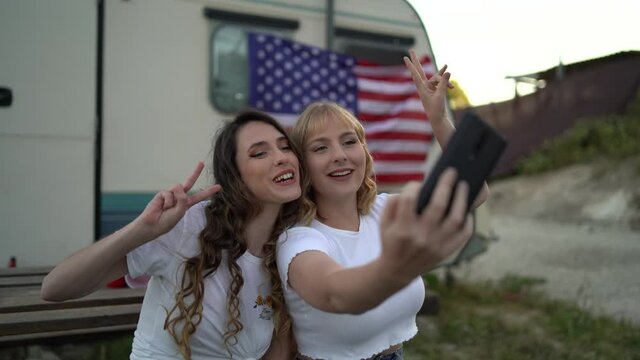 Spanish friends doing a funny selfie near a camp trailer with an American flag shot in 4K