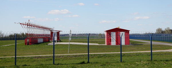 Beautiful small airport runway buildings with airstrip lights and safety fence at Sunny spring day on blue sky background
