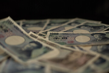 Blurred focus of pile of Japanese money in 1000 yen bills and 10000 yen bills on black background in soft focus