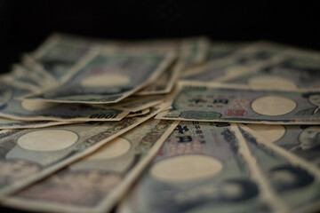Blurred focus of pile of Japanese money in 1000 yen bills and 10000 yen bills on black background in soft focus