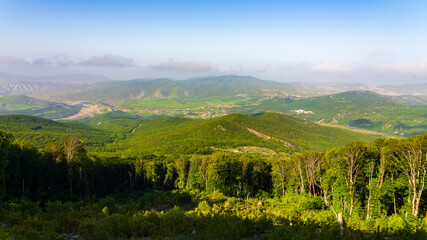 Naklejka premium View of green mountains and villages in the valley. Wide angle panorama