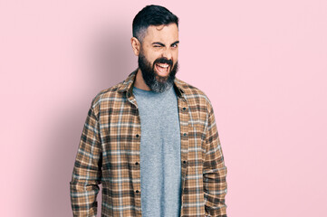 Hispanic man with beard wearing casual shirt winking looking at the camera with sexy expression, cheerful and happy face.