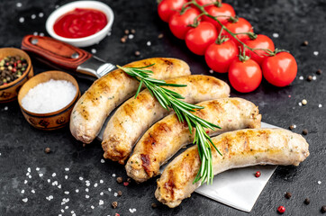 grilled sausages on a meat knife on a stone background