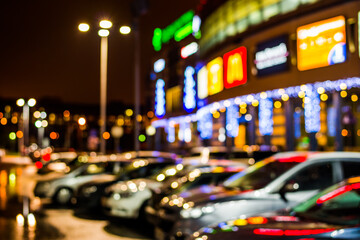 Rainy night in the parking shopping mall, rows of parked cars. Defocused image