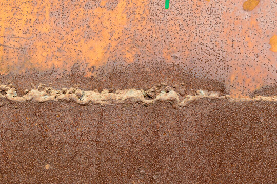 Weld seam of two sheets of metal. Old paint, rust.
