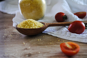 Couscous in a wooden spoon and in a glass jar.
