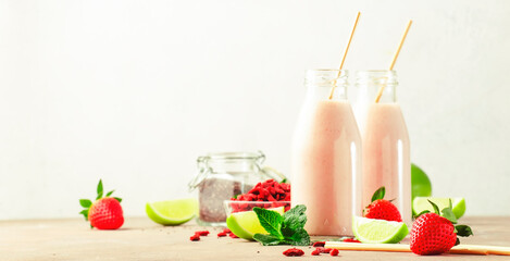 Healthy blended diet smoothie drink with strawberry and goji berries, chia seeds and lime. Glass bottles with eco fendley straws