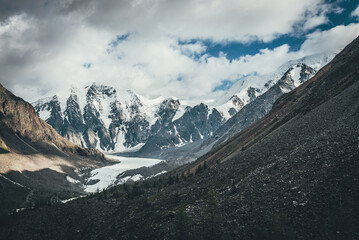Beautiful mountain landscape with glacier tongue and great snowy mountains in sunlight in cloudy...