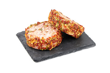 Raw meat patties with spices slate board, pork cutlets isolated on white