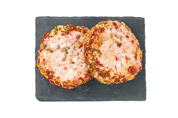 Raw meat patties with spices slate board, pork cutlets isolated on white