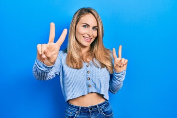 Young caucasian woman wearing casual clothes smiling looking to the camera showing fingers doing victory sign. number two.