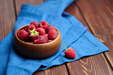 Fresh raspberries in wooden bowl on brown table. Red ripe raspberries, sweet berries