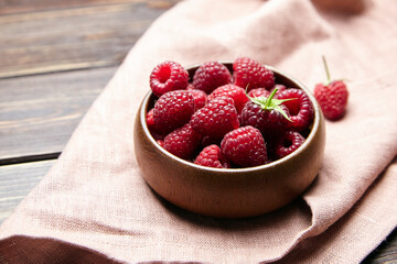 Fresh raspberries in wooden bowl on brown table. Red ripe raspberries, sweet berries
