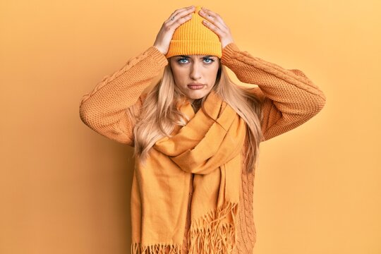 Young caucasian woman wearing wool winter sweater and cap suffering from headache desperate and stressed because pain and migraine. hands on head.