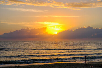 Sunset evening sea are disappearing into the clouds, gloomy atmosphere and cause an orange glow shone with reflected wave of the sea, a beautiful sparkling.