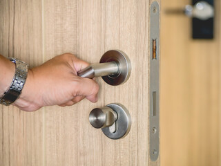 Man hand holding silver handle of door to opening or closing  the door of condominium or hotel in city for security.