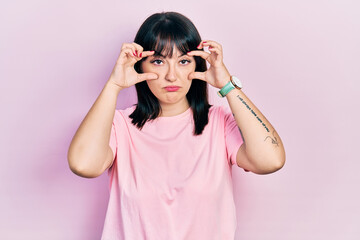 Young hispanic woman wearing casual clothes trying to open eyes with fingers, sleepy and tired for morning fatigue