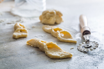 Cutting from fresh dough sweet angel wings. Homemade pastries.
