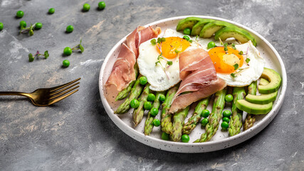 Breakfast table with fried egg with asparagus spears and prosciutto. ketogenic diet lunch concept. menu, top view