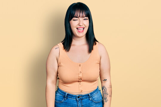 Young hispanic plus size woman wearing casual clothes winking looking at the camera with sexy expression, cheerful and happy face.