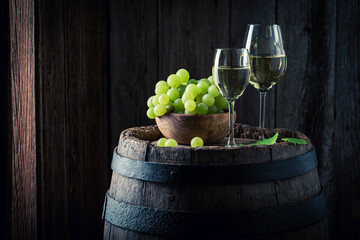 White wine with green grapes on barrel. Wine industry.