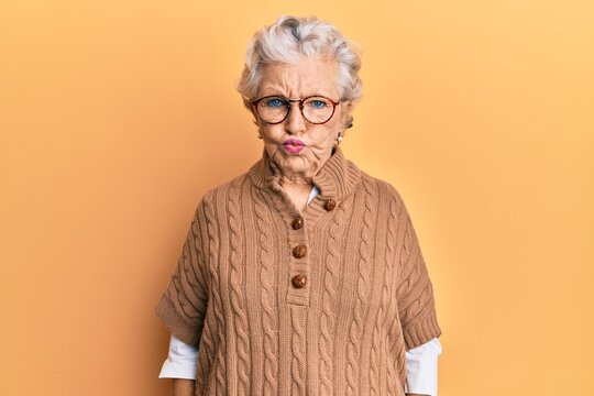 Senior grey-haired woman wearing casual clothes and glasses making fish face with lips, crazy and comical gesture. funny expression.