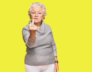 Senior grey-haired woman wearing casual winter sweater showing middle finger, impolite and rude...