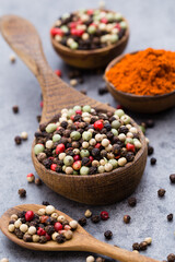 Peppercorn mix in a wooden bowl on grey table.