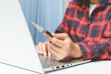 Asian young woman shopping online on labtop on white desk in the living room. Financial transactions through device. Easy shopping and covenient concept