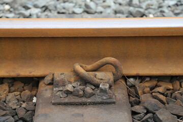A closeup view of a section of metal railway tied to a wooden sleeper above the ballast.