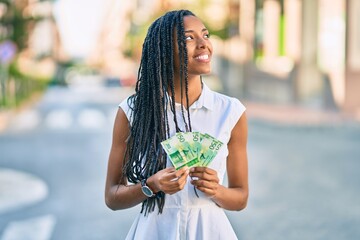 Young african american woman smiling happy holding norwegian 50 krona banknotes at the city.