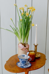Blue porcelain tableware burning candle yellow daffodils on a wooden table