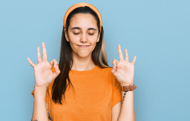 Young hispanic woman wearing casual clothes relaxed and smiling with eyes closed doing meditation gesture with fingers. yoga concept.