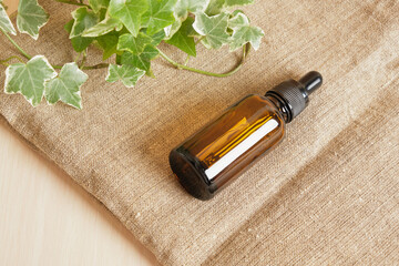 Brown glass bottle dropper with cosmetic oil and plant