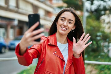 Young hispanic woman doing video call using smartphone at the city.