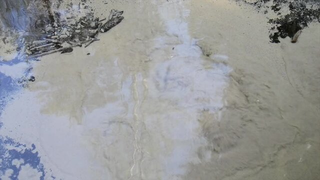 Crystal clear water with bubbling boiling bubbles from an underground source. green trees reflect in the water.