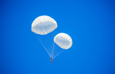 Skydiving. Flying parachutists against the background of the blue sky and mountains. Extreme sport and entertainment.