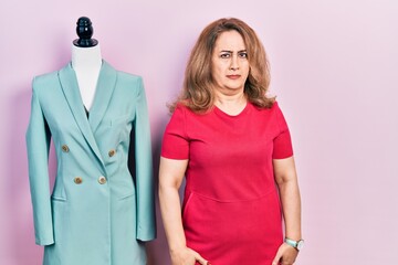 Middle age caucasian woman standing by manikin skeptic and nervous, frowning upset because of...