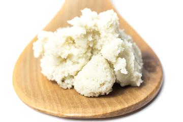Shea butter isolated on white background on wooden spoon, unrefined, close up