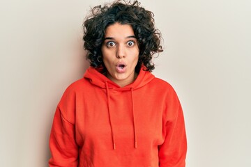 Fototapeta na wymiar Young hispanic woman with curly hair wearing casual sweatshirt afraid and shocked with surprise expression, fear and excited face.