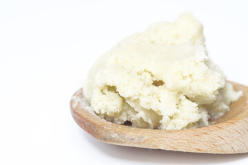 Shea butter isolated on white background on wooden spoon, unrefined, close up