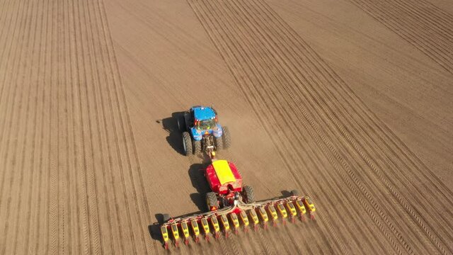 Tractor with seeder in the field, aerial view.