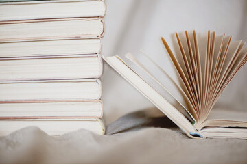 Pile of books with one open book lying near.