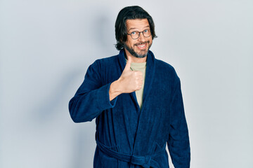 Middle age caucasian man wearing bathrobe and glasses doing happy thumbs up gesture with hand. approving expression looking at the camera showing success.