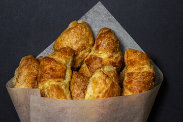 Croissants on a black surface. Baking on a dark background. Sweet pastries in a paper envelope