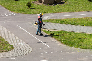lawnmover man worker cutting dry grass with lawn mower