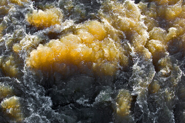 Das aufgewühlte, schlammige Wasser hinter einer Staustufe