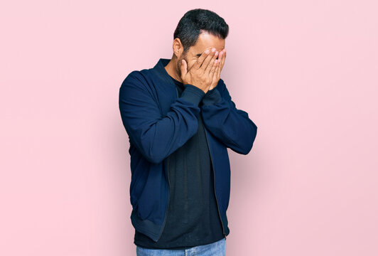 Young hispanic man wearing casual clothes with sad expression covering face with hands while crying. depression concept.